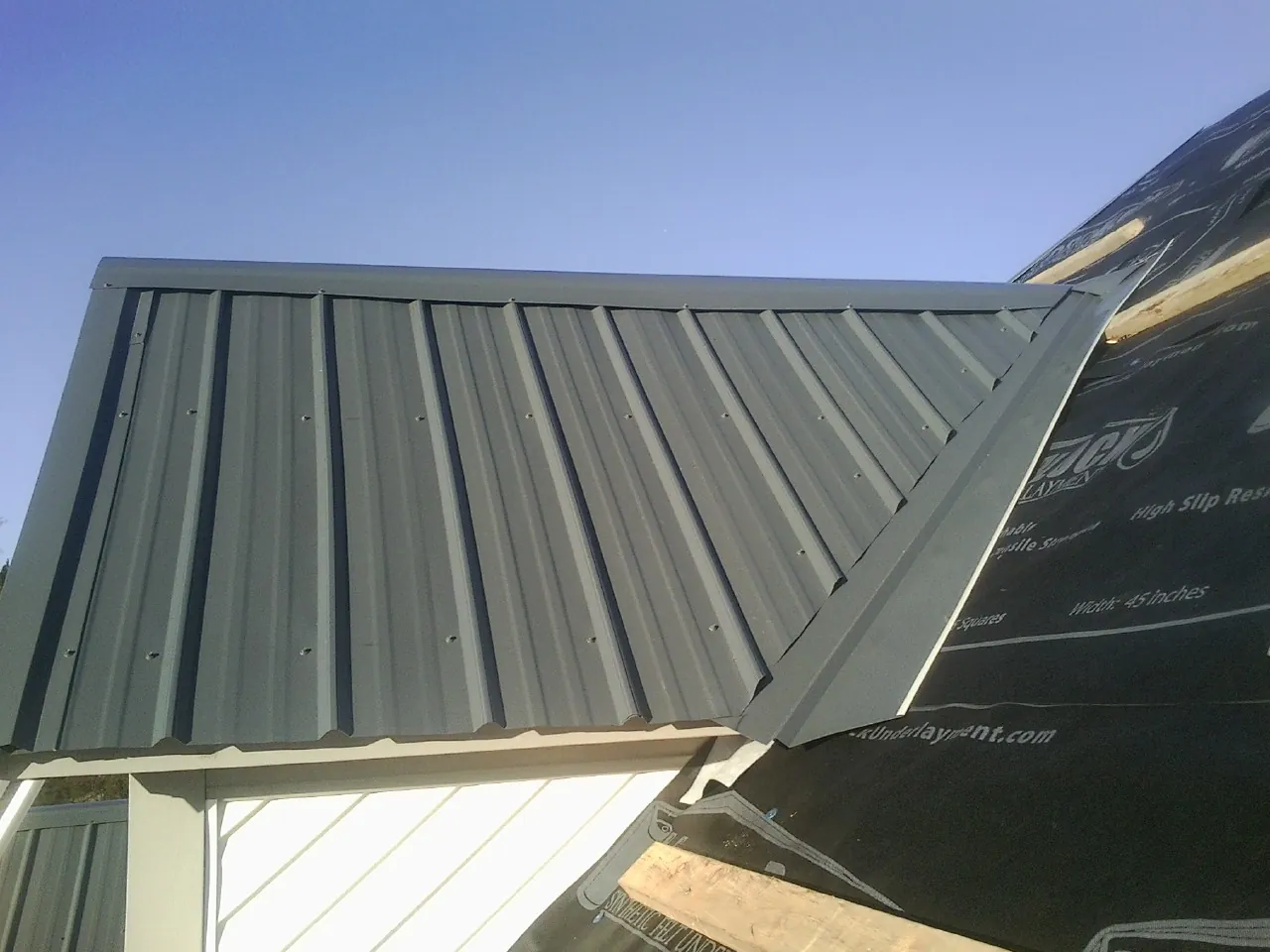 Gray metal roof panels going on over a garage gable in Halls