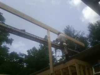 Carpenter setting a ridge beam over a new addition frame — Ice Dam Removal by Roofing Brothers in Halls