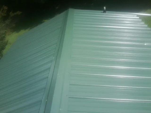 New green metal panels meeting at the ridge of a roof — Flat Roof Repair work by our crew in Halls