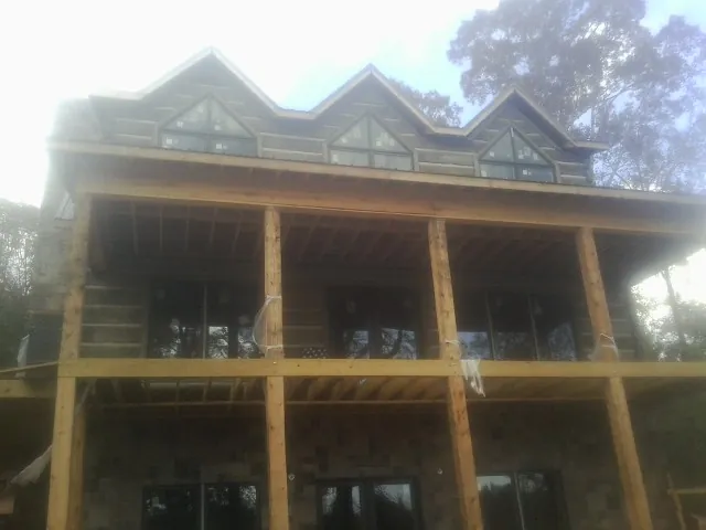 Dormers and porch framing on a large log home under construction — Roof Coating work by our crew in Halls