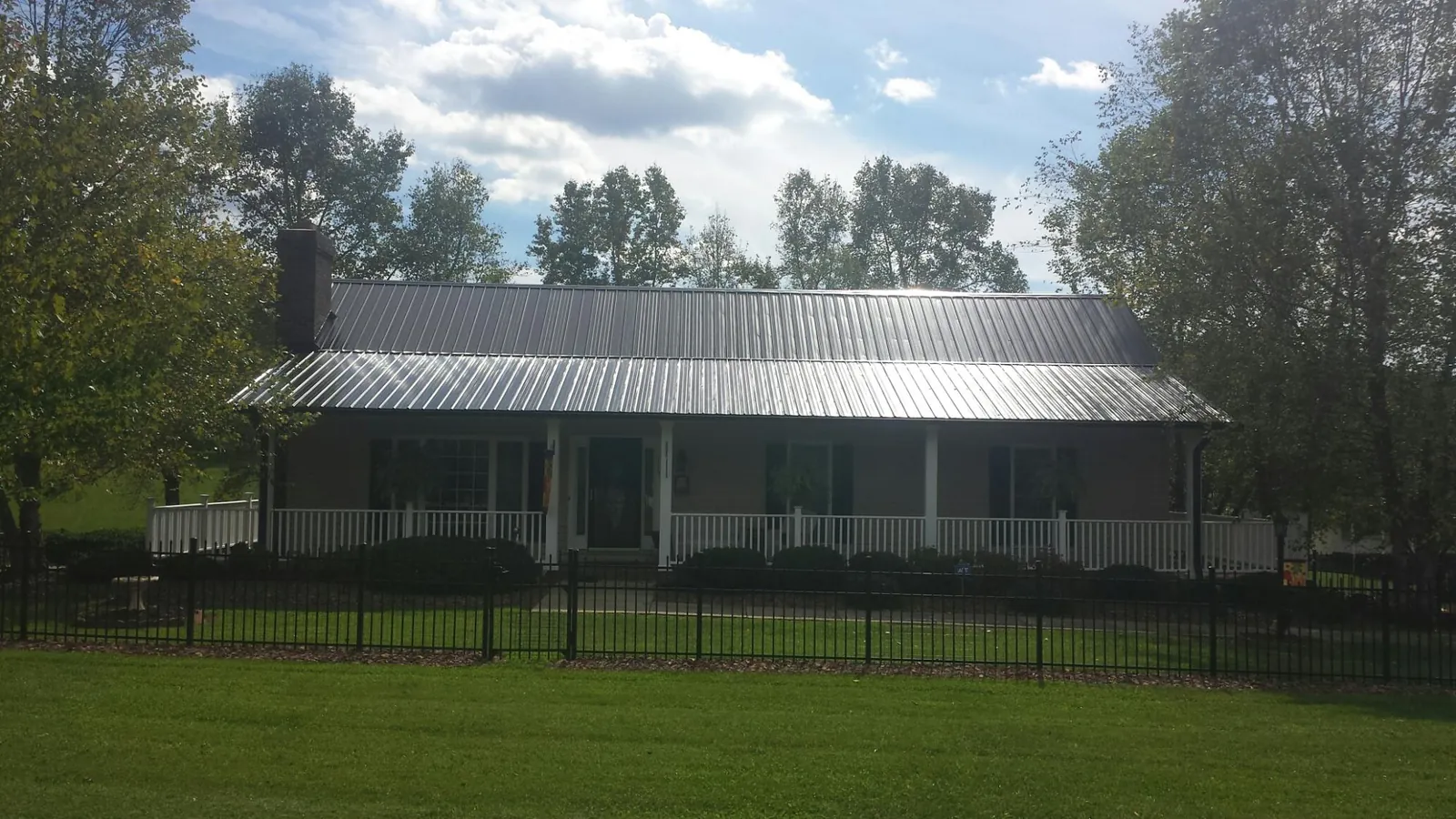Gray metal roof on a brick ranch with a full width front porch — Gutter Guard Installation work by our crew in Halls