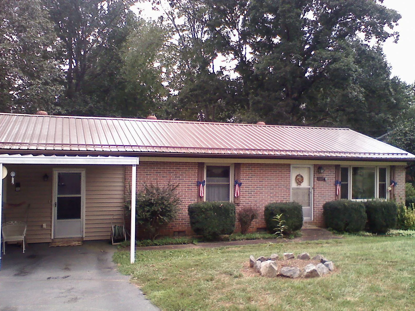 Bronze metal roof and carport on a brick ranch home — Roof Repair work by our crew in Halls