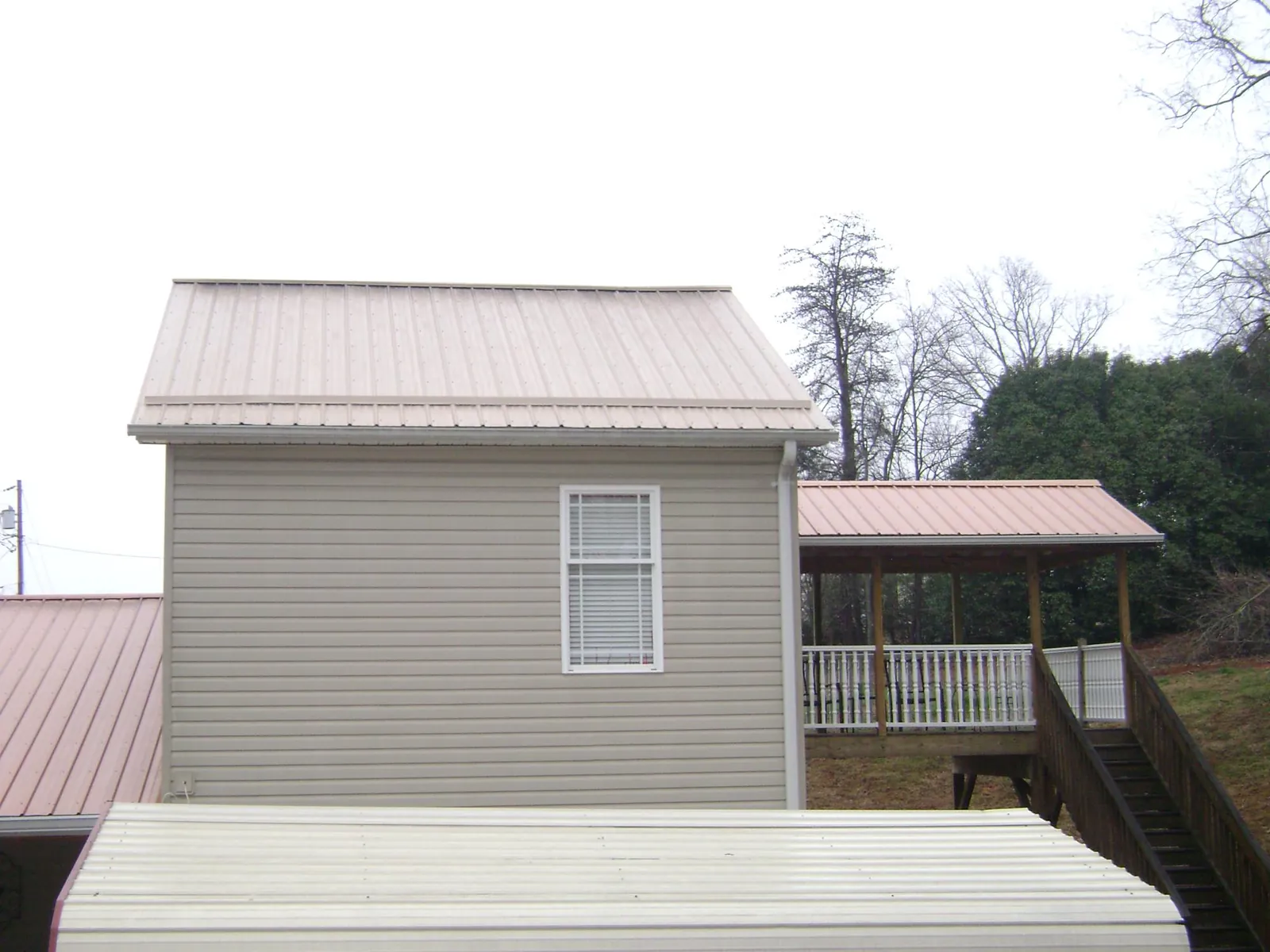 Tan metal roofs on a two story addition and attached porch, from a Roof Replacement job in Halls