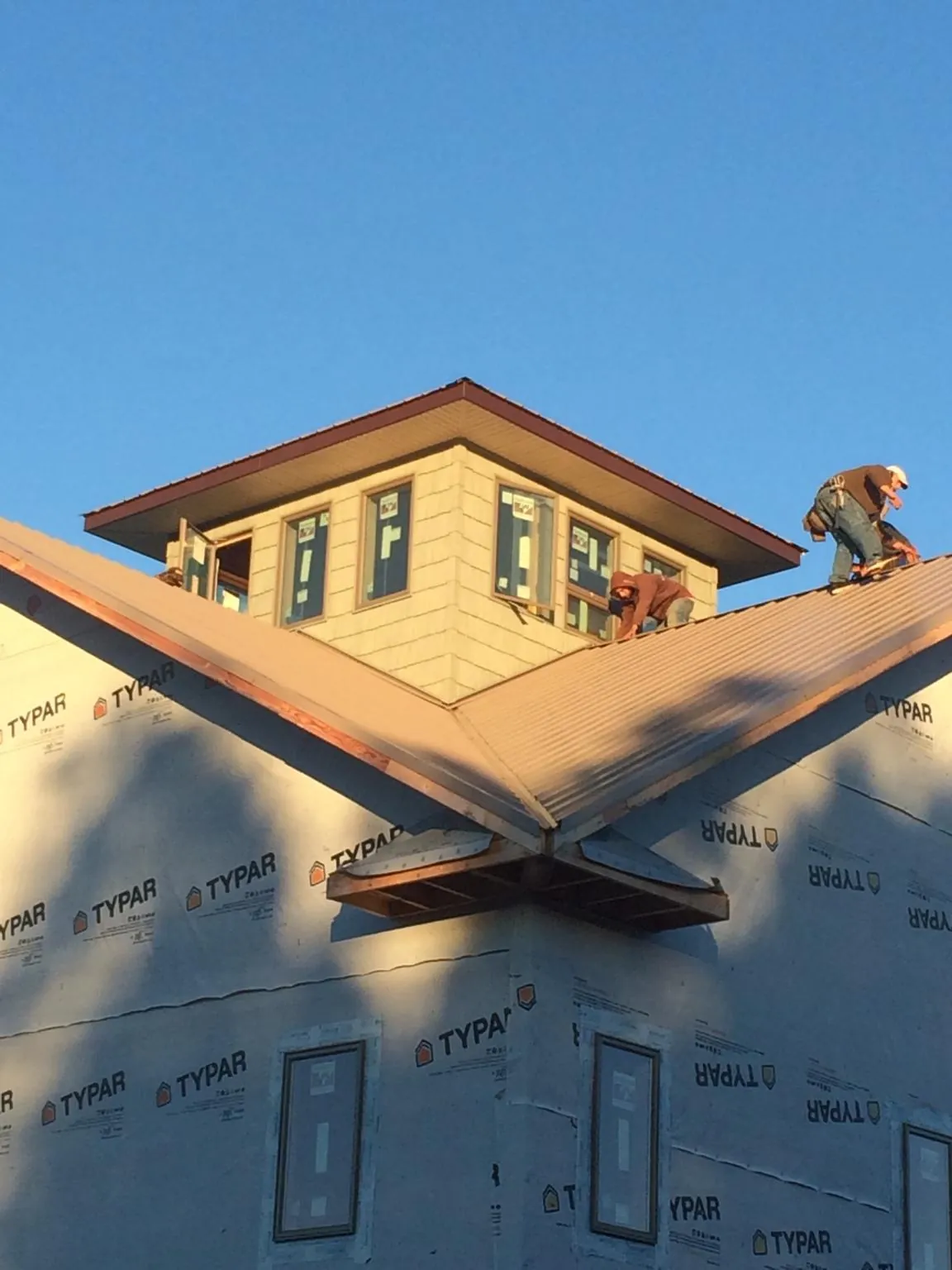Roofers working around a rooftop cupola on a new metal roof at sunset — Roof Waterproofing in Halls by Roofing Brothers